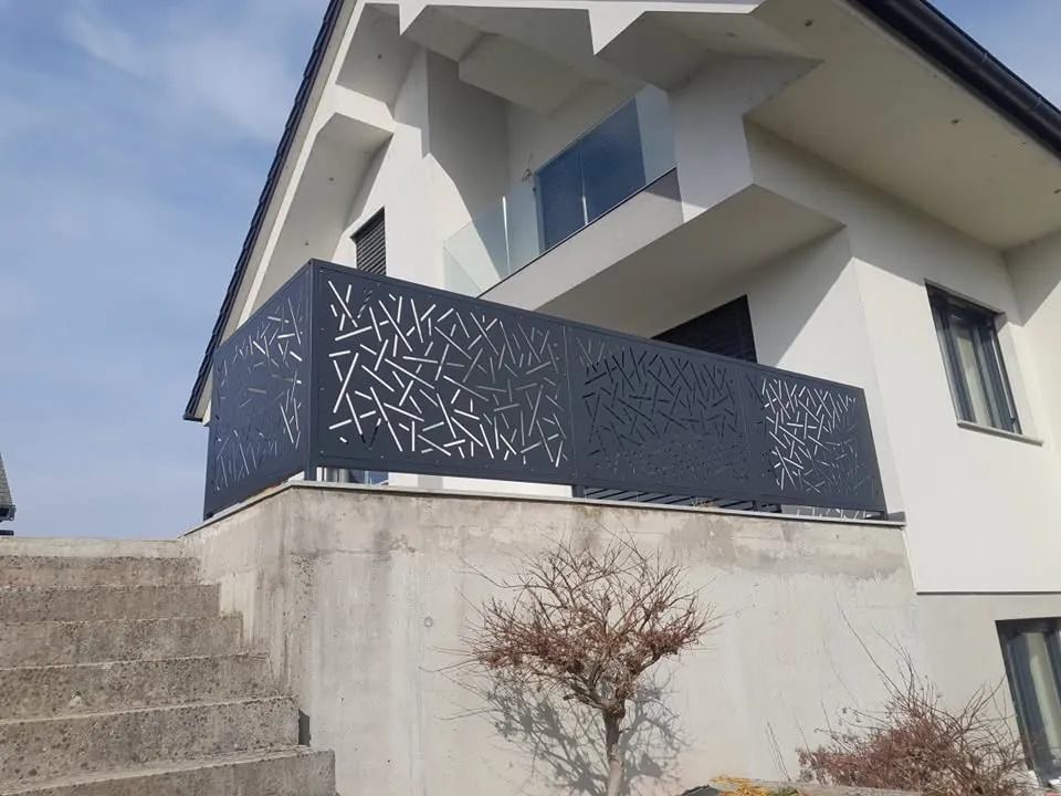 Balkonska ograja iz polnih kovinskih polj z izrezanim vzorcem prepletenih vej nad stopniščem